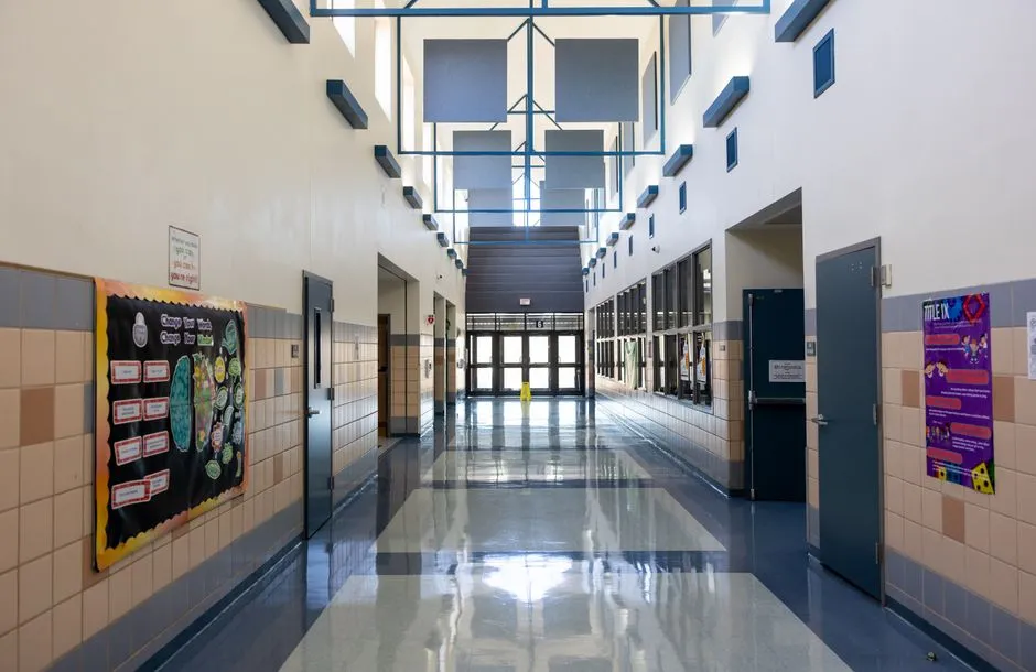 Bright empty school hallway lined with lockers and bulletin boards