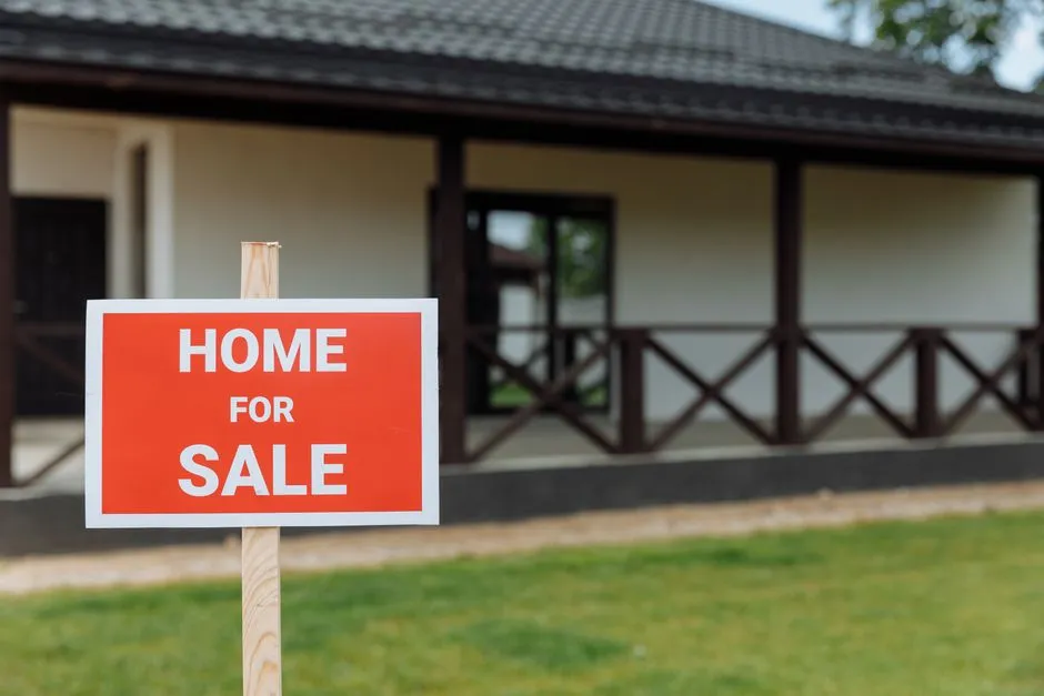 A red for sale sign posted in front of a house